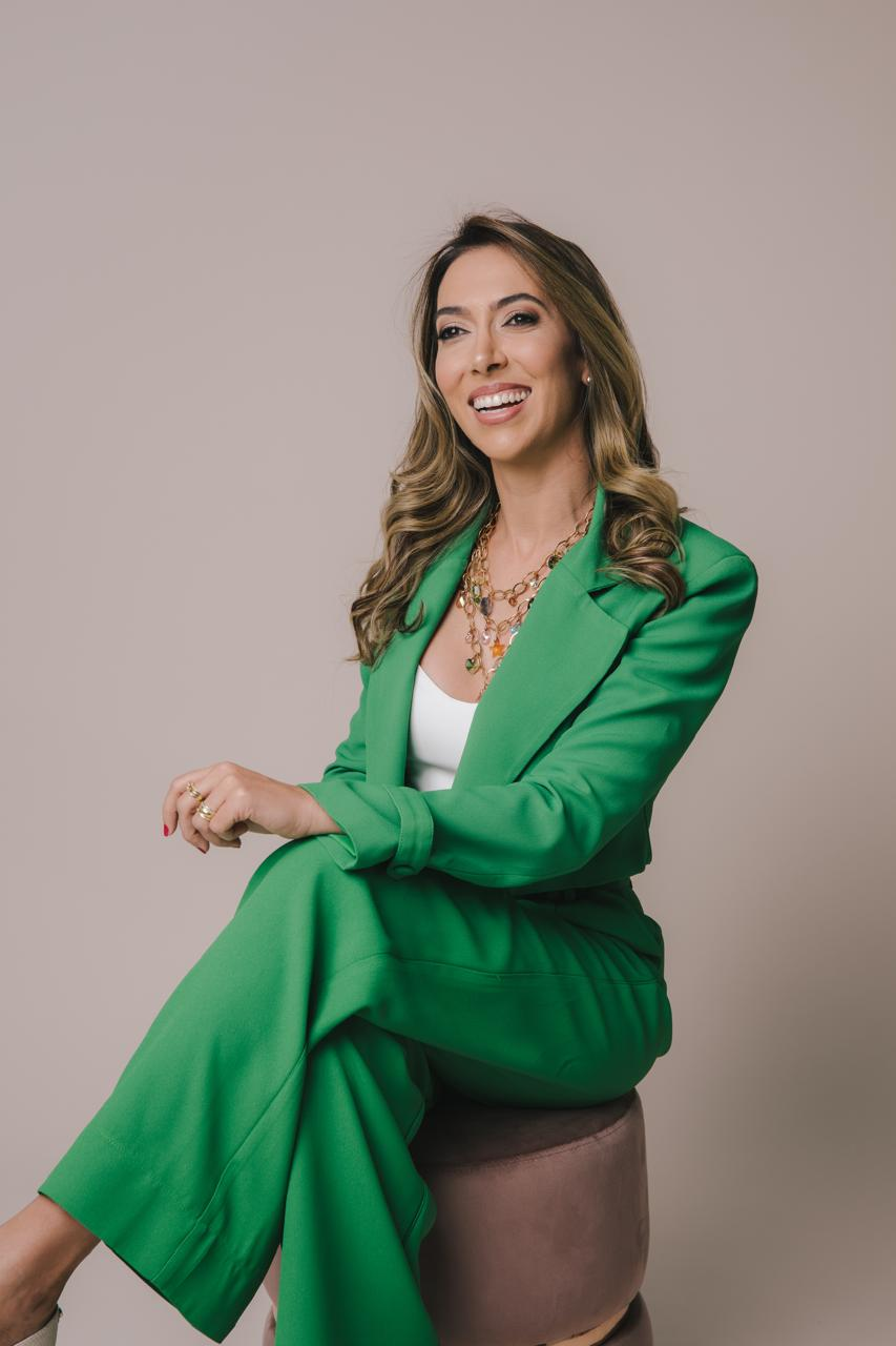 Dra. Larissa Alvarenga sentada, vestindo conjunto verde
